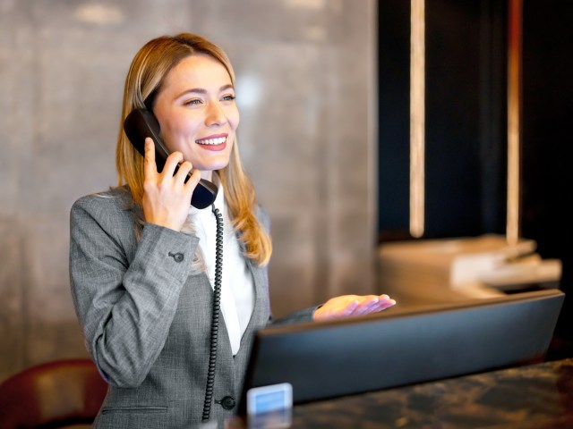 Front desk receptionist at hotel speaking on phone