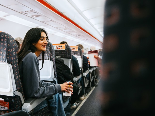 Airline passenger talking to seatmate across aisle