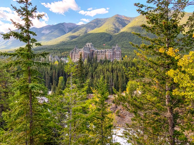 View through forest of Fairmont Banff Springs hotel in distance