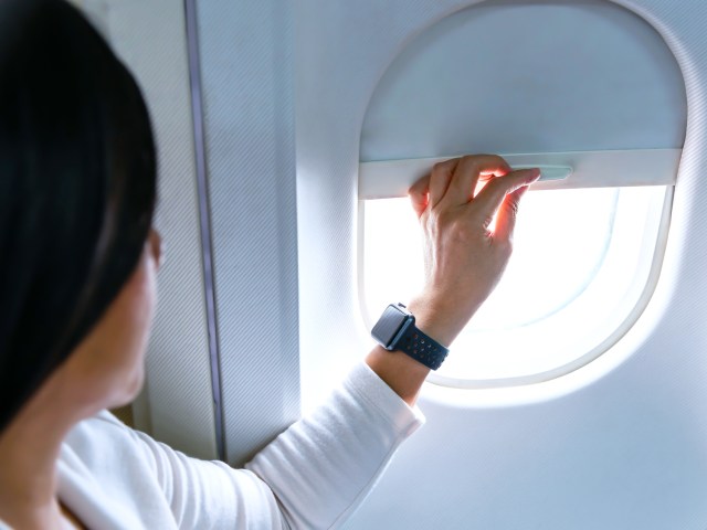 Airline passenger adjusting window shade