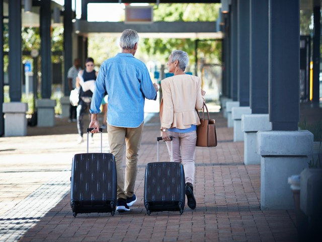 Man and woman rolling suitcases on sidewalk