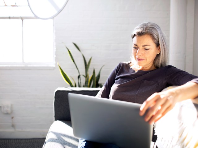 Woman sitting on couch using laptop computer