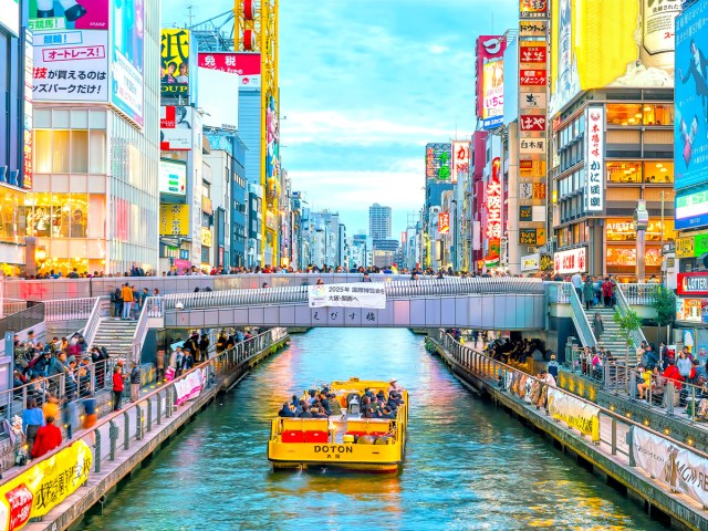 Boat cruising on river through busy downtown Osaka, Japan 