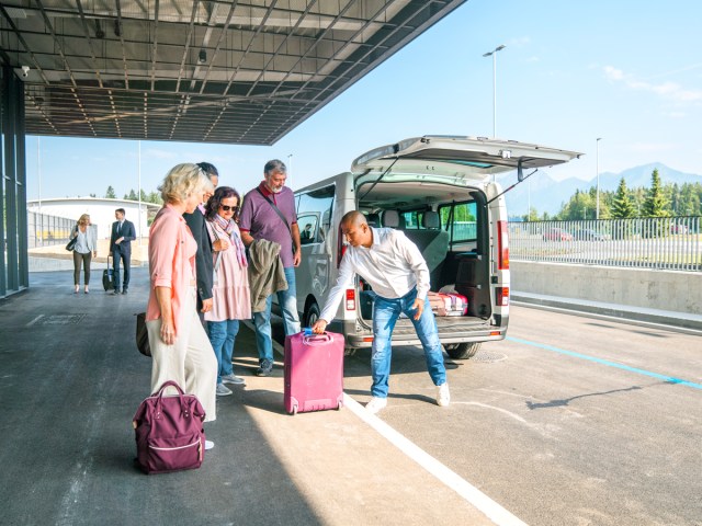 Hotel shuttle driver helping passengers with luggage at airport