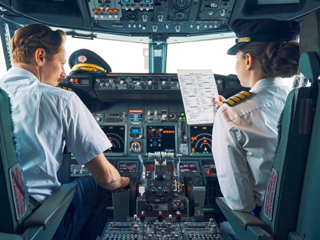 Pilot and co-pilot reviewing checklist in airplane cockpit