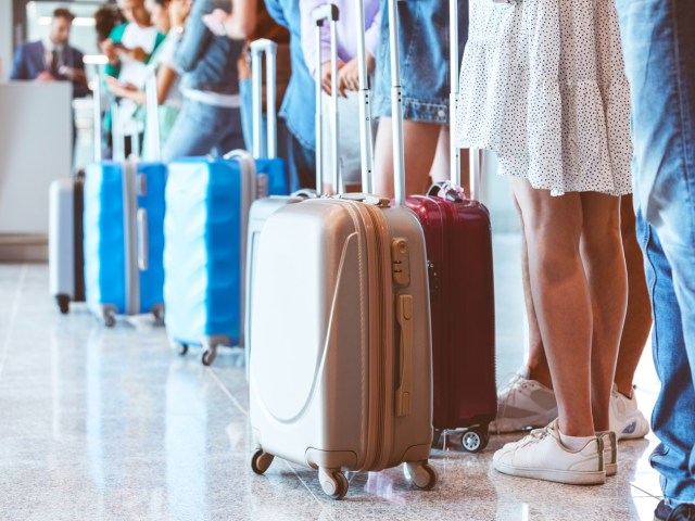 Travelers standing in airport queue with luggage