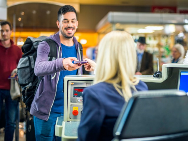 Airline passenger handing passport to check-in agent at airport