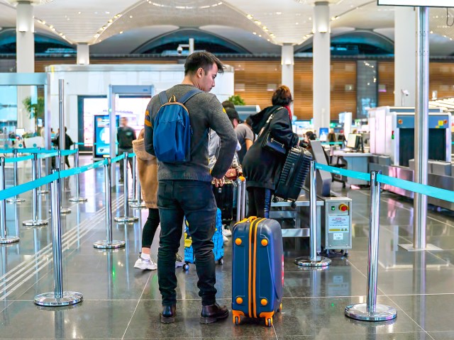 Travelers standing with luggage in airport security line