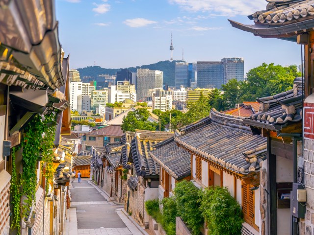 Narrow street between traditional Korean architecture, overlooking modern cityscape of Seoul