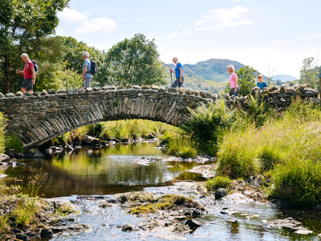 Group walking across stone bridge over river