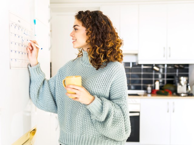 Woman marking calendar in kitchen