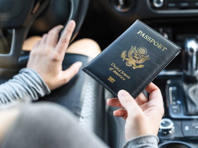 Driver in car holding U.S. passport