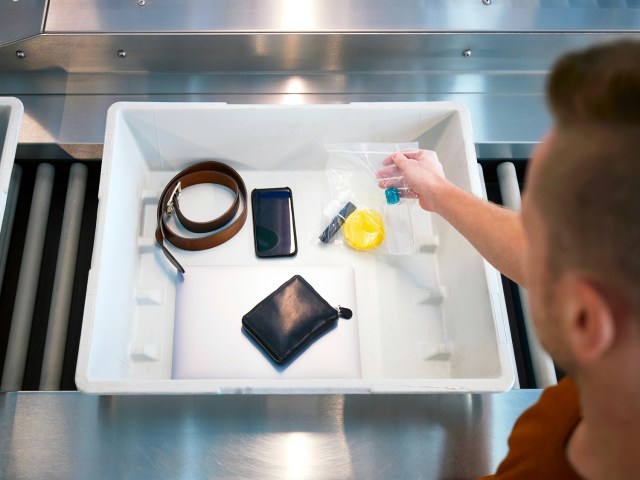 Passenger placing items in bin on airport security belt