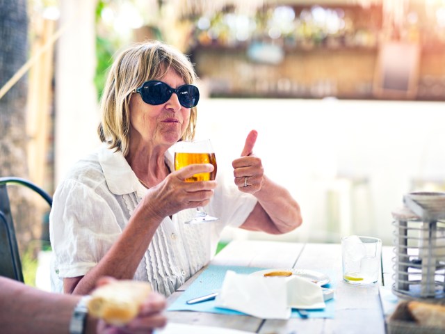 Woman drinking beer and giving a thumbs up 