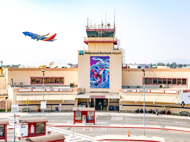 Terminal building at Hollywood Burbank Airport in California, with jet taking off behind