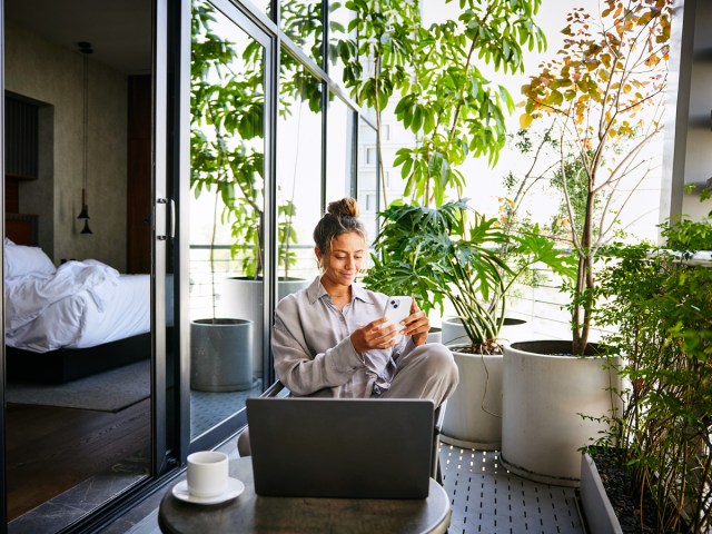 Hotel room guest working on laptop and phone