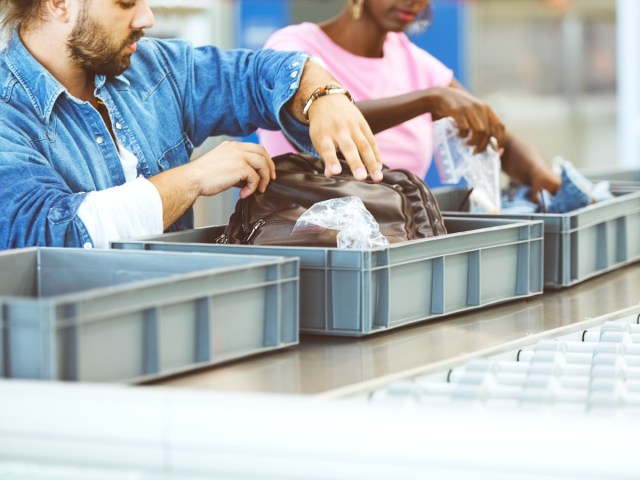 Airline passengers placing items in bins to be screened at TSA security