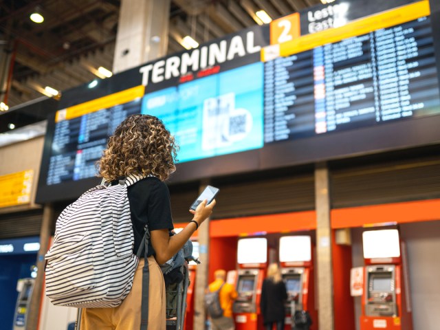 Airline passenger looking at departures board in terminal