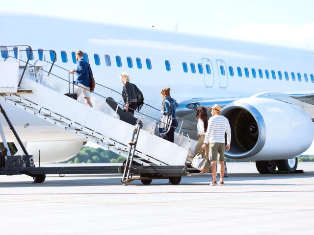 Passengers boarding airplane via air stairs