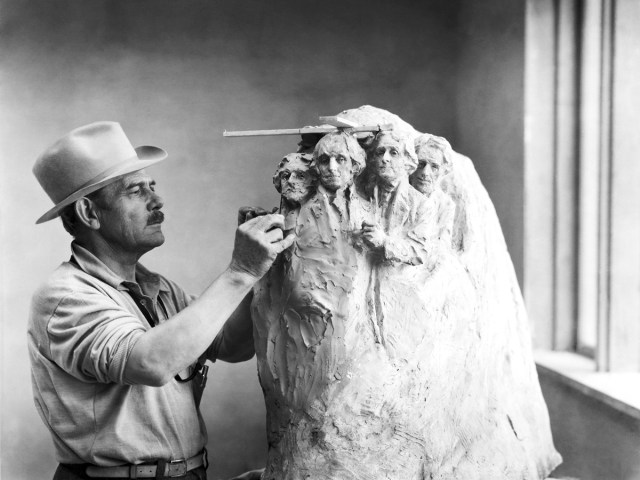 Historical image of sculptor Gutzon Borglum working on model of Mount Rushmore