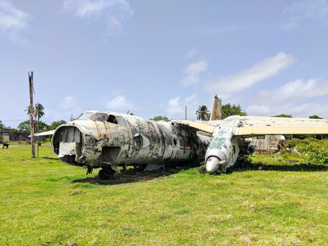Abandoned aircraft on grassy field at Pearls Airport, Grenada