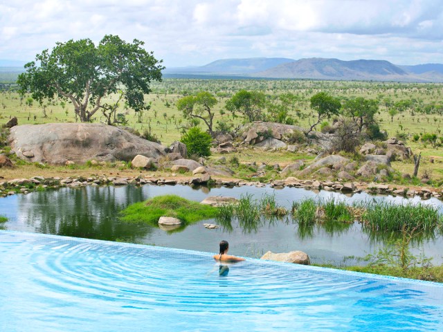 Woman in infinity pool overlooking Serengeti National Park at Four Seasons Safari Lodge Serengeti