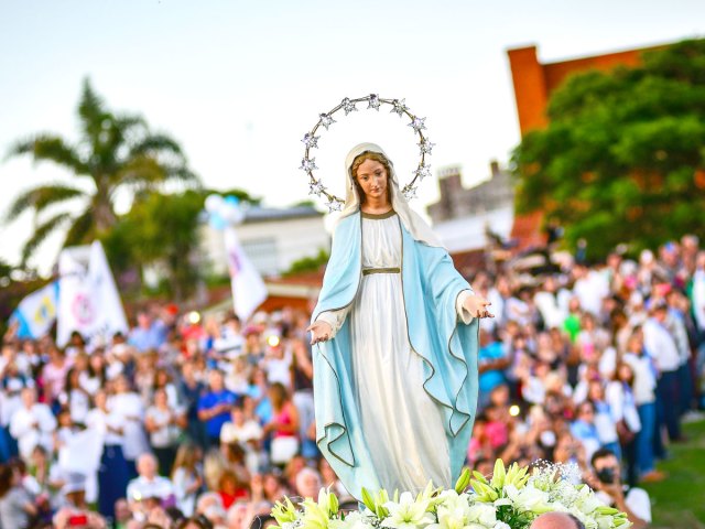 Crowds gather behind statue of the Virgin Mary