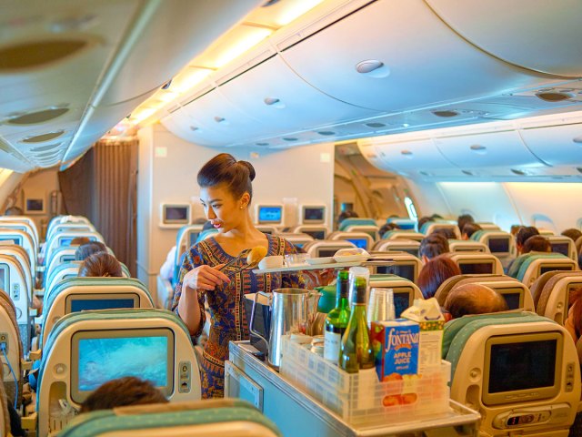Singapore Airlines flight attendant serving meals to economy-class passengers