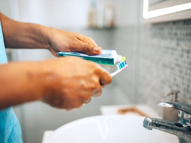 Person squeezing toothpaste onto toothbrush