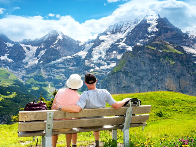 Couple sitting on bench admiring the Swiss Alps