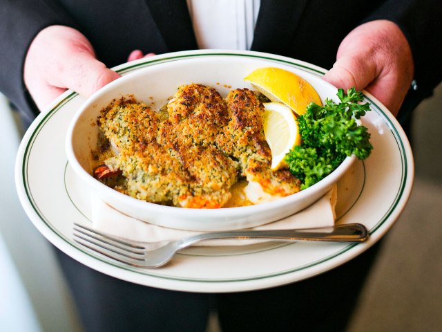 Server holding plate of shrimp De Jonghe
