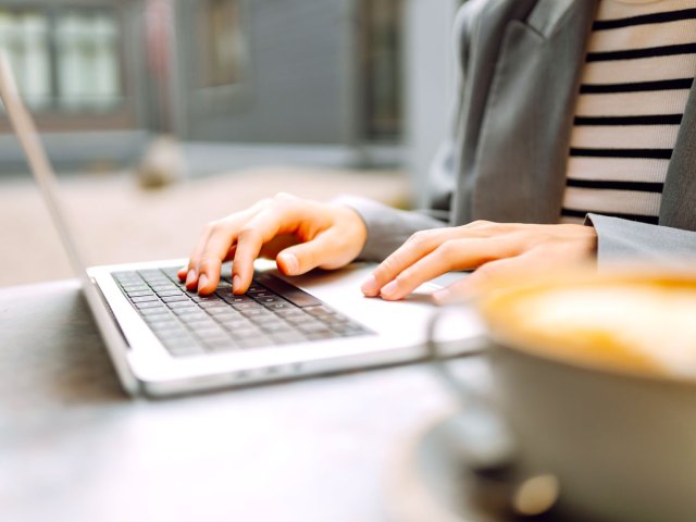 Person using laptop computer next to cup of coffee
