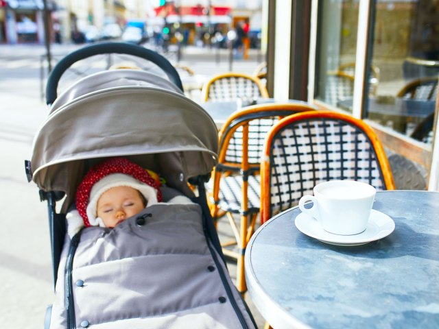 Baby in stroller next to cafe table outdoors