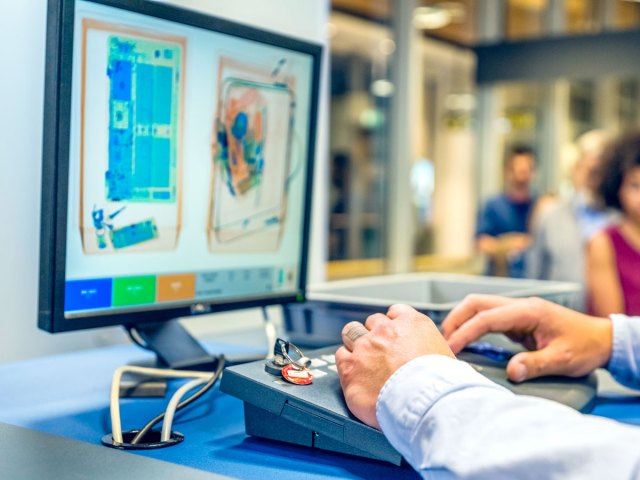 Security officer inspecting screen with X-ray images of bags