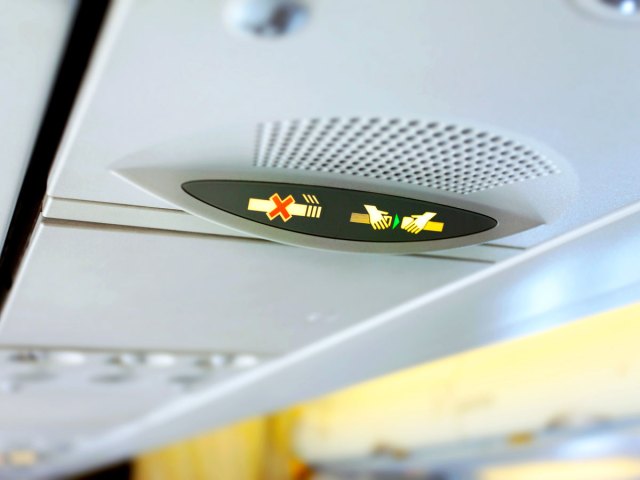 Close-up view of seatbelt and no-smoking sign on aircraft