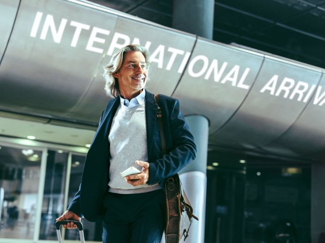 Man standing beside sign for international arrivals in airport terminal