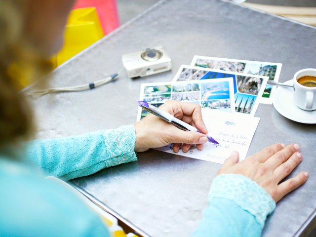 Traveler writing postcards with on table with cup of coffee