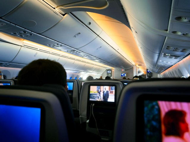 Passengers watching entertainment screens in dim airplane cabin