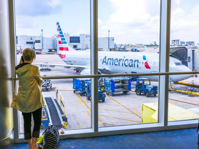 Passenger looking out terminal window at American Airlines Boeing 737 parked at gate