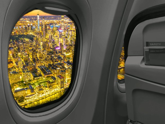 View of bright city lights at night from airplane window